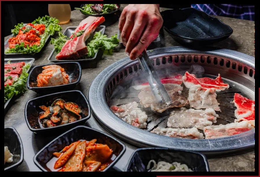 Marinated short rib on the grill surrounded by banchan